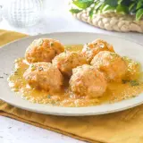 Sabrosas albóndigas de pollo en una salsa dorada, espolvoreadas con perejil fresco. Un plato casero listo para disfrutar.