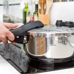 Mano cerrando la tapa de una olla express para cocinar lentejas. Cocina rápida y sabrosa.