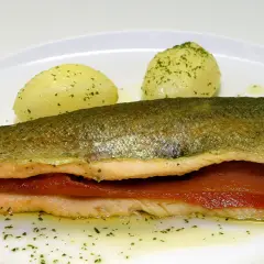 Trucha a la navarra rellena de jamón, servida con patatas cocidas y perejil picado.
