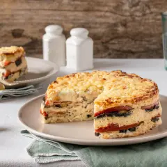 Pastel de verduras en capas, gratinado con queso, servido en un plato.