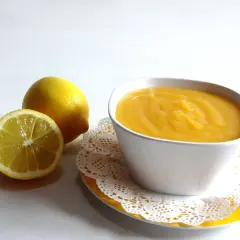 Un tazón de crema de limón, con limones frescos al lado.