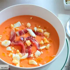 Salmorejo cremoso con jamón serrano y huevo duro picado, ingredientes clave de esta delicia.