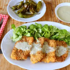 Escalopines al cabrales crujientes, servidos con ensalada verde y pimientos asados. ¡Un plato delicioso!