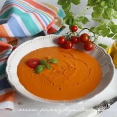 Crema de queso de tomate, decorada con tomates cherry y albahaca, lista para disfrutar.