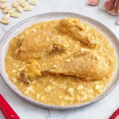 Pollo a la pepitoria servido en un plato, con trozos de huevo duro y almendras esparcidas.