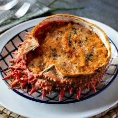 Txangurro a la donostiarra, un delicioso relleno de marisco gratinado en su propio caparazón, adornado con perejil picado.