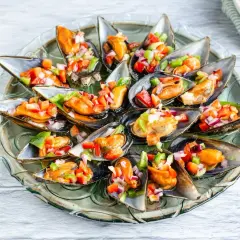 Mejillones a la vinagreta, frescos y coloridos, servidos en una bandeja de cristal.