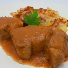 Solomillo de cerdo a la cerveza bañado en salsa, acompañado de patatas gratinadas con bacon y perejil.