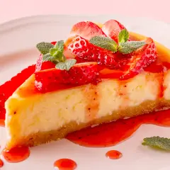 Deliciosa tarta de queso con fresas frescas y salsa de fresa, decorada con hojas de menta.