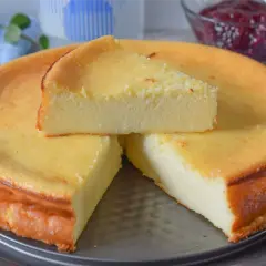 Tarta de queso al horno, dorada y esponjosa, con una porción servida. Un postre casero perfecto.