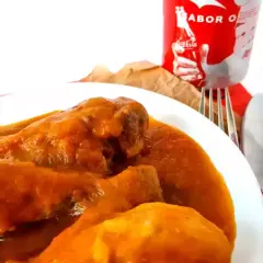 Sabroso pollo a la Coca Cola en un plato blanco, acompañado de cubiertos y una lata de Coca Cola.