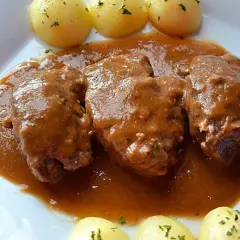 Carrilleras de ternera estofadas en salsa, acompañadas de patatas cocidas y espolvoreadas con perejil. Un plato casero que invita a disfrutar.