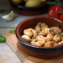 Deliciosos langostinos al ajillo, servidos en cazuela de barro con ajo y perejil.