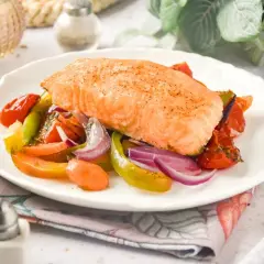 Delicioso salmón al horno con verduras coloridas: tomates, pimientos y cebolla morada. Un plato saludable y lleno de sabor.