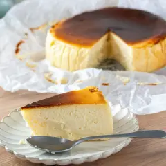 Deliciosa tarta de queso en freidora de aire, con una porción servida en plato y cuchara.