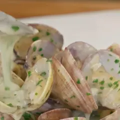 Almejas en salsa verde, con una cremosa salsa blanca y perejil picado, listas para ser servidas.