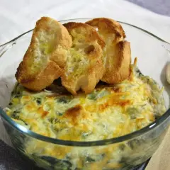 Delicioso plato de espinacas con bechamel gratinado, coronado con tostadas de pan.