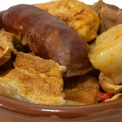 Un reconfortante puchero andaluz en cazuela de barro, con chorizo, tocino y trozos de carne.