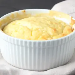 Un esponjoso soufflé de patatas recién horneado en un ramekin blanco, listo para ser disfrutado.