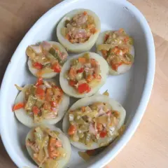 Patatas rellenas con verduras y jamón, listas para hornear. Un plato casero y delicioso.
