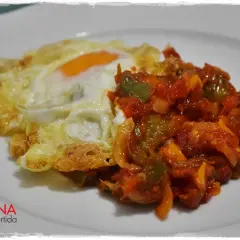 Huevo frito con un sofrito de pimientos y tomate. Un plato sencillo y delicioso, perfecto para cualquier momento del día.
