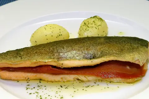 Trucha a la navarra rellena de jamón, servida con patatas cocidas y perejil picado.