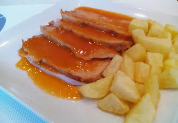 Jamon asado al horno, jugoso y tierno, bañado en salsa y acompañado de patatas fritas crujientes. ¡Un plato delicioso!