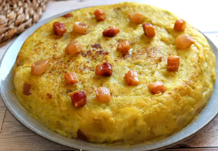 Un delicioso trinxat de la Cerdanya, una tortilla dorada con trocitos de panceta, lista para saborear.