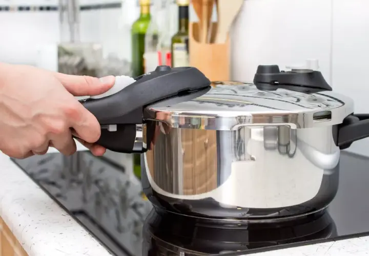 Mano cerrando la tapa de una olla express para cocinar lentejas. Cocina rápida y sabrosa.