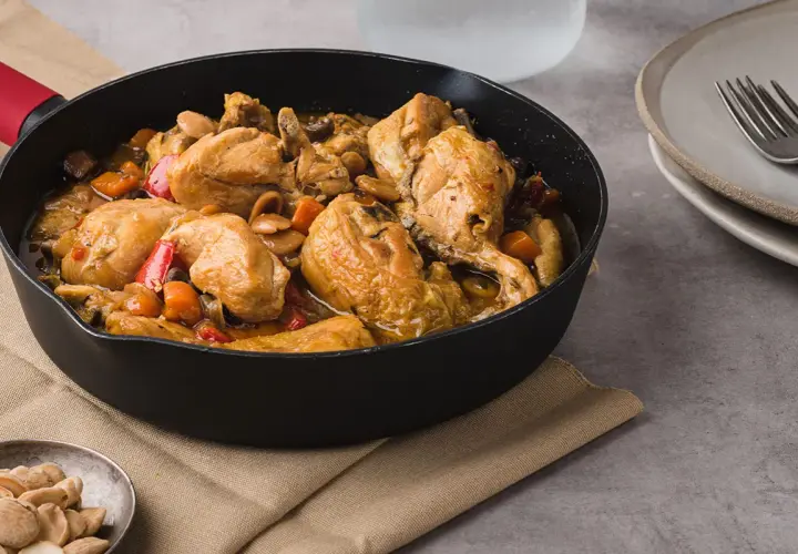 Sabroso pollo con almendras y verduras en una sartén, listo para servir.