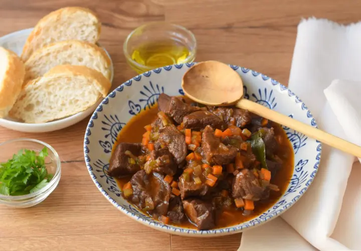 Un reconfortante plato de ternera en salsa, con trozos tiernos de carne, zanahoria y apio, servido con pan y perejil fresco.