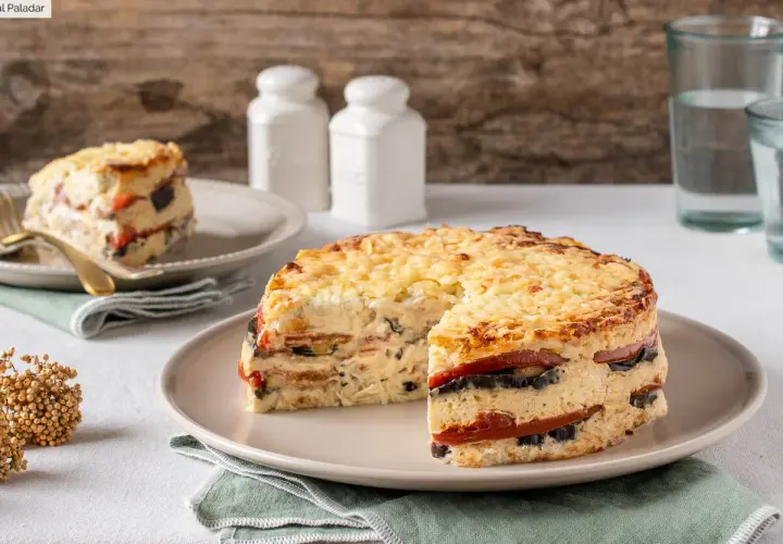 Pastel de verduras en capas, gratinado con queso, servido en un plato.