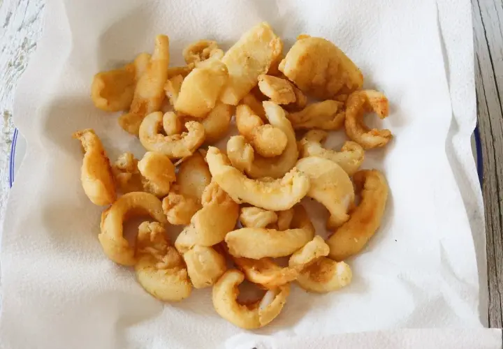 Un plato lleno de chocos fritos, crujientes y dorados, reposando sobre papel absorbente. ¡Un aperitivo delicioso!
