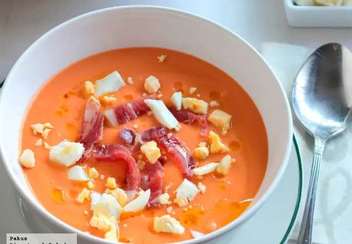 Salmorejo cremoso con jamón serrano y huevo duro picado, ingredientes clave de esta delicia.