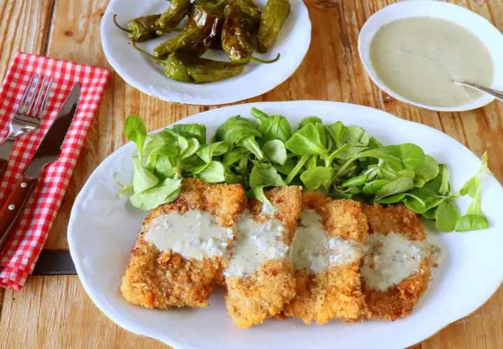 Escalopines al cabrales crujientes, servidos con ensalada verde y pimientos asados. ¡Un plato delicioso!