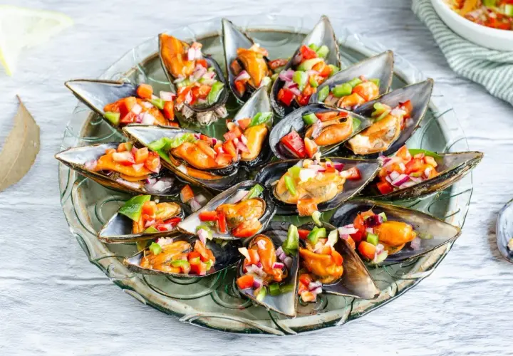 Mejillones a la vinagreta, frescos y coloridos, servidos en una bandeja de cristal.