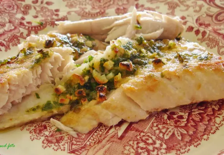 Deliciosa ventresca al horno, jugosa y dorada, con un aderezo verde de hierbas y ajo.