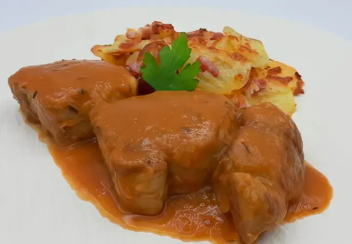Solomillo de cerdo a la cerveza bañado en salsa, acompañado de patatas gratinadas con bacon y perejil.
