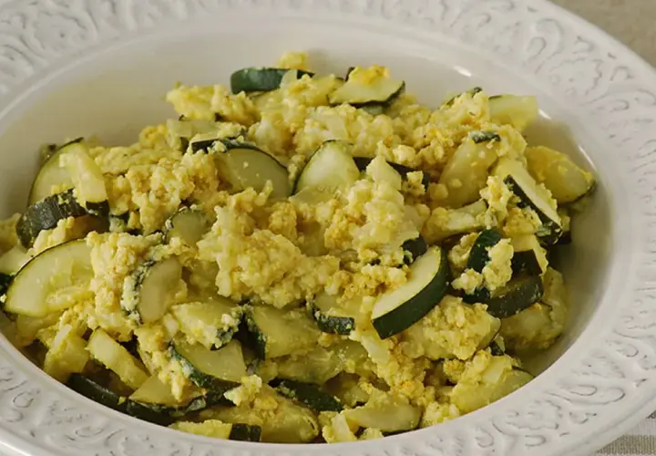 Zarangollo murciano, un plato casero de calabacín y huevo revuelto, servido en un cuenco blanco con relieve.