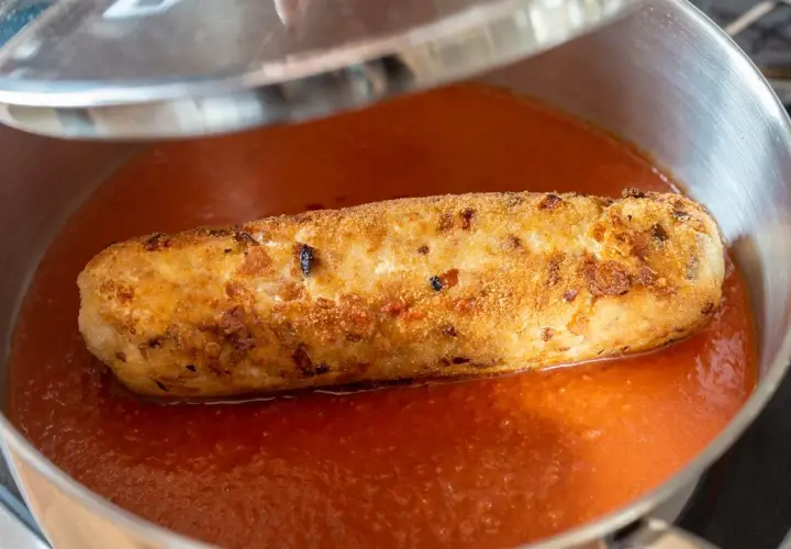 Rollo de bonito casa consuelo, dorado y crujiente, nadando en una salsa de tomate casera en una sartén.