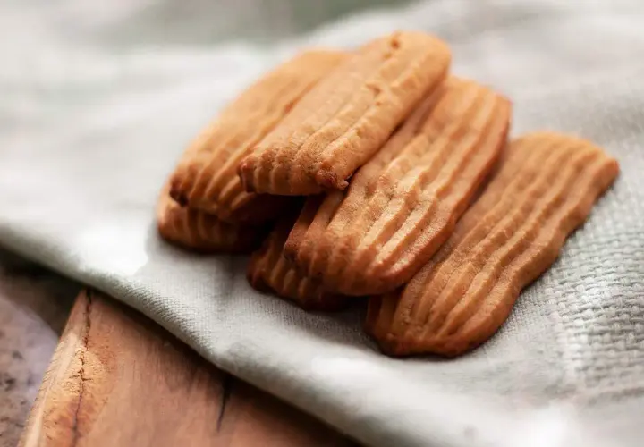 Galletas de mantequilla receta: deliciosas galletas doradas con surcos, apiladas sobre una tela clara.