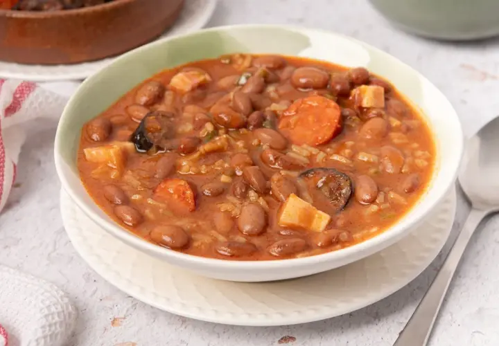 Un tazón humeante de alubias pintas con chorizo, patatas y arroz. Un plato reconfortante y sabroso.