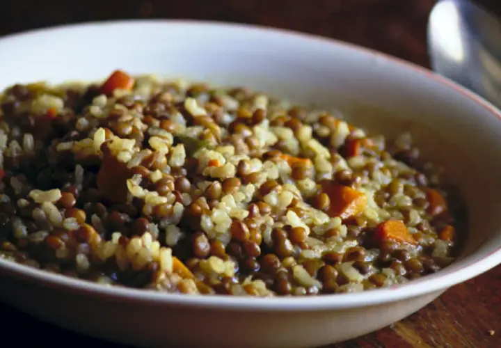 Un plato humeante de lentejas con arroz y trozos de zanahoria, listo para ser disfrutado.
