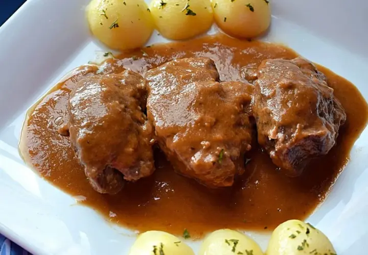 Carrilleras de ternera estofadas en salsa, acompañadas de patatas cocidas y espolvoreadas con perejil. Un plato casero que invita a disfrutar.