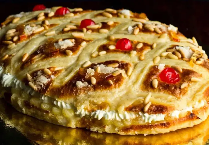 Deliciosa coca de Sant Joan rellena de crema, decorada con piñones, cerezas rojas y azúcar.