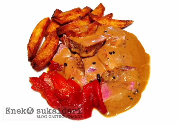 Delicioso solomillo a la pimienta bañado en salsa cremosa, acompañado de patatas rústicas y pimientos rojos asados.
