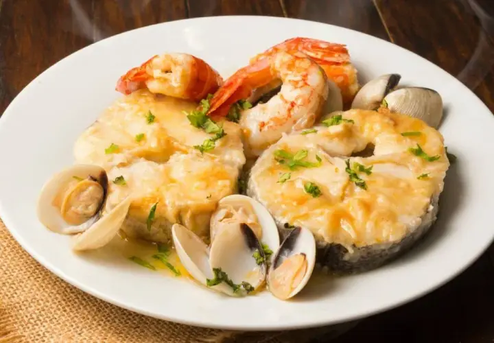 Merluza a la marinera con almejas y gambas, un plato delicioso y aromático, listo para disfrutar.