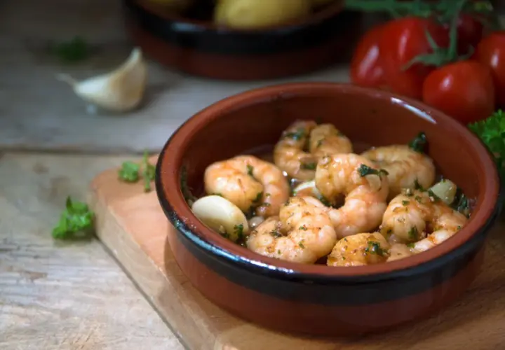Deliciosos langostinos al ajillo, servidos en cazuela de barro con ajo y perejil.