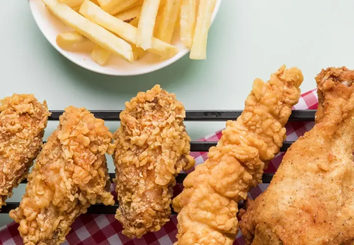 Crujientes alitas de pollo fritas y papas fritas doradas, un festín irresistible para cualquier amante de la comida rápida.