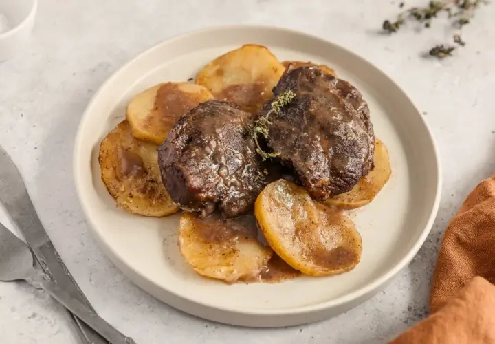 Deliciosas galtas al horno, tiernas y jugosas, servidas sobre rodajas de patata doradas y bañadas en su propia salsa.